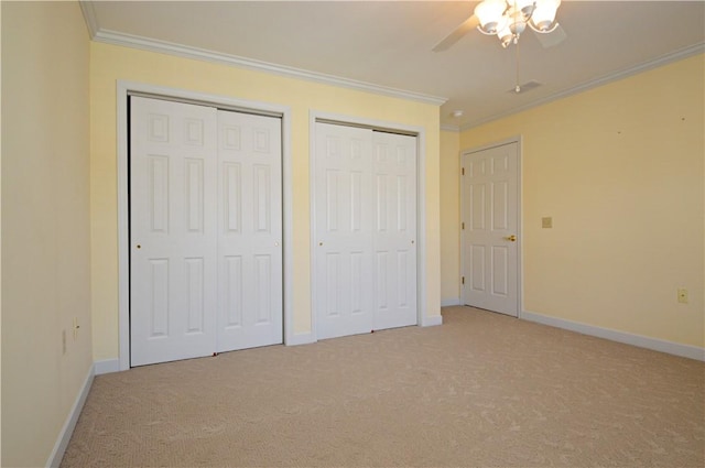 unfurnished bedroom with light colored carpet, baseboards, multiple closets, and ornamental molding