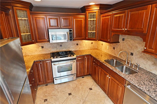 kitchen with decorative backsplash, light stone countertops, stainless steel appliances, and a sink