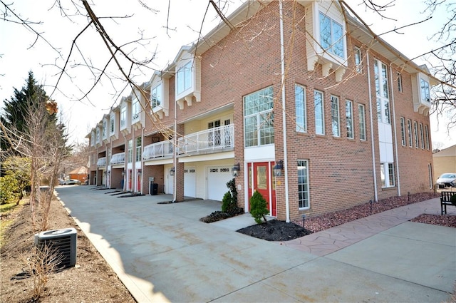 view of home's exterior featuring cooling unit, brick siding, and a garage