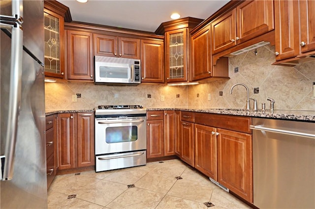 kitchen with light stone counters, tasteful backsplash, appliances with stainless steel finishes, and a sink