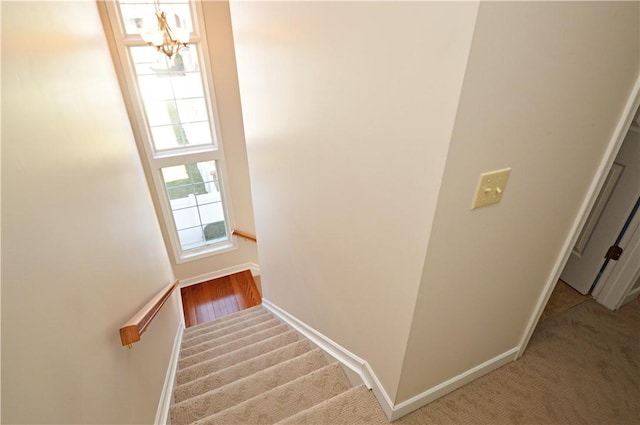 stairway featuring carpet flooring, baseboards, and an inviting chandelier