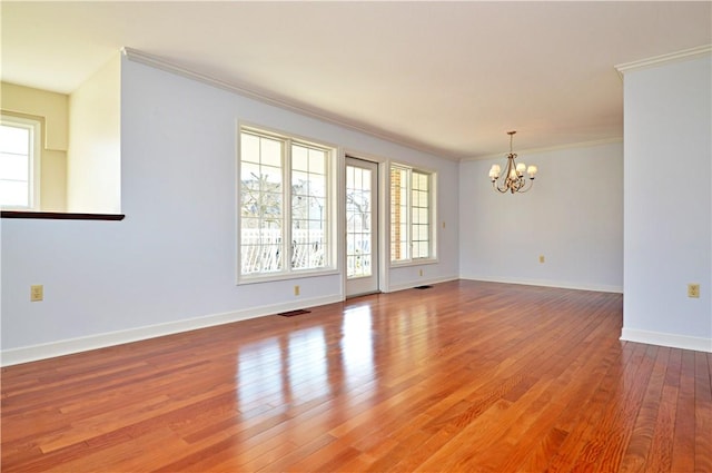 unfurnished room with visible vents, crown molding, baseboards, an inviting chandelier, and hardwood / wood-style flooring