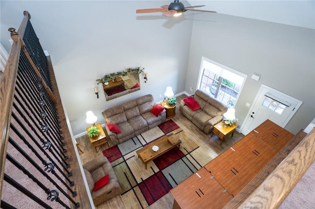 living area with baseboards, a fireplace, high vaulted ceiling, and a ceiling fan