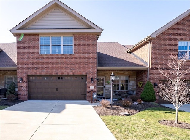 traditional-style home with brick siding, an attached garage, concrete driveway, and roof with shingles