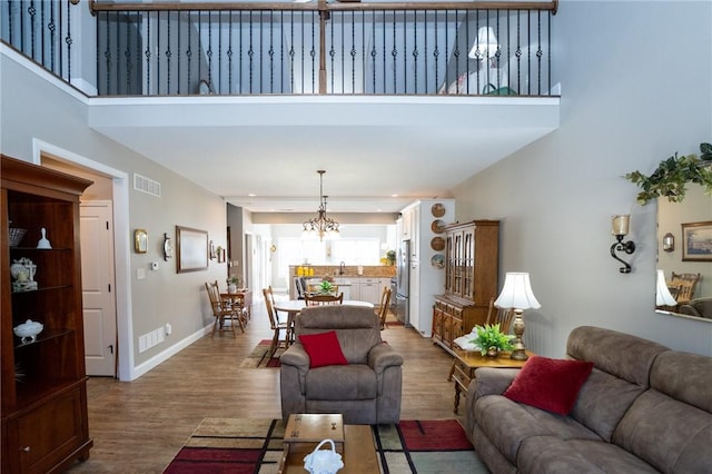 living area with visible vents, a towering ceiling, and wood finished floors