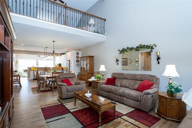 living area with a high ceiling, a notable chandelier, wood finished floors, and visible vents