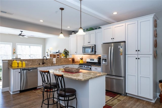 kitchen with dark wood finished floors, a peninsula, visible vents, and stainless steel appliances