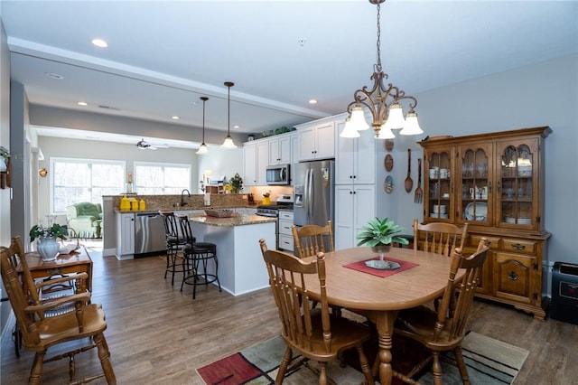 dining area featuring dark wood-style floors, recessed lighting, and ceiling fan with notable chandelier