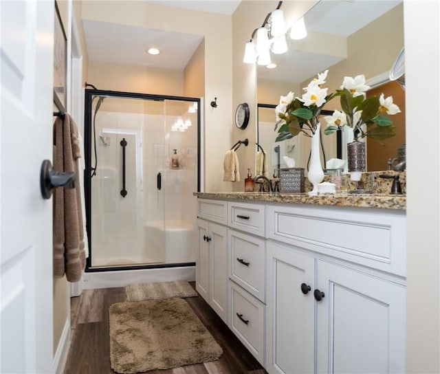 bathroom featuring wood finished floors, a stall shower, and vanity