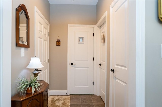 corridor with dark tile patterned floors and baseboards