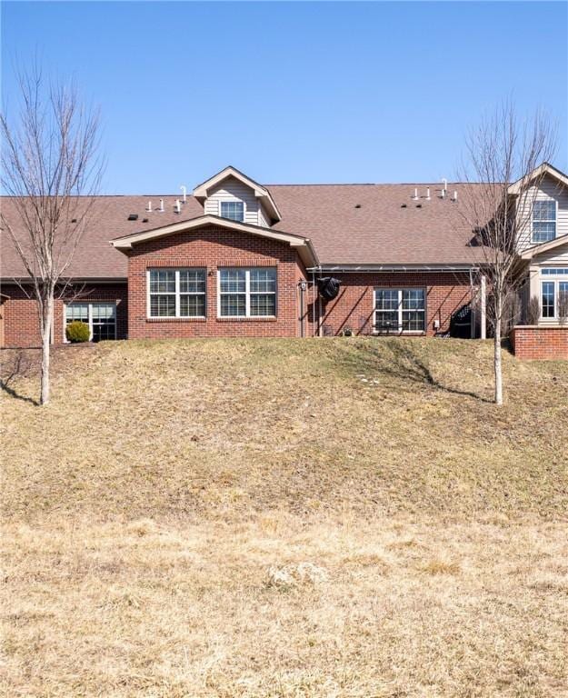 rear view of property featuring brick siding and roof with shingles