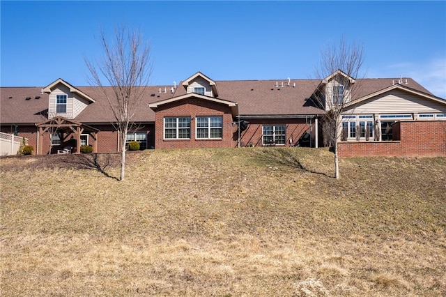 back of house with a yard and brick siding