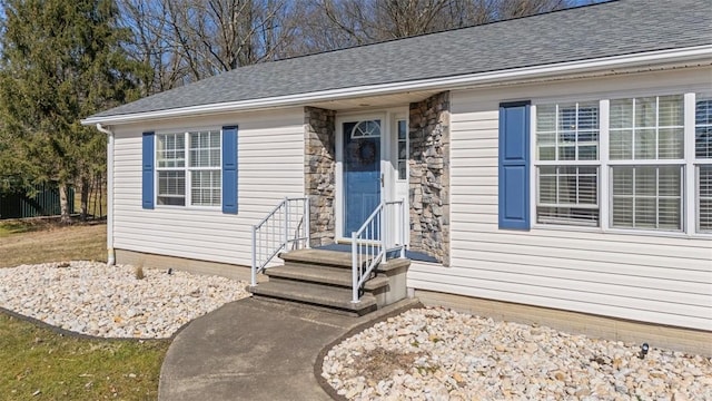 property entrance featuring stone siding and a shingled roof