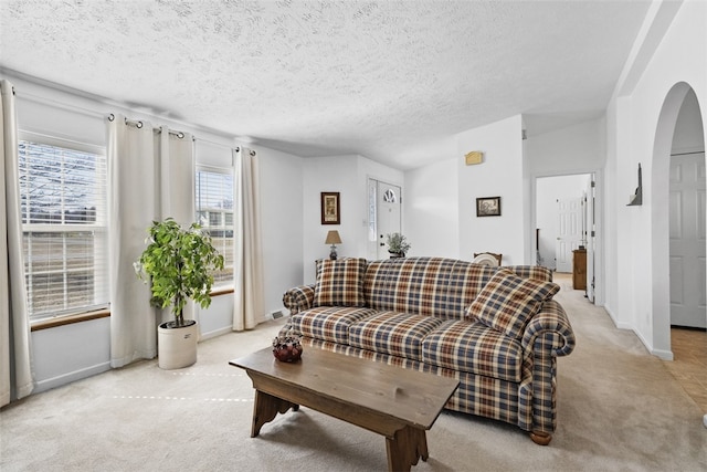 living room featuring light carpet, a textured ceiling, and baseboards