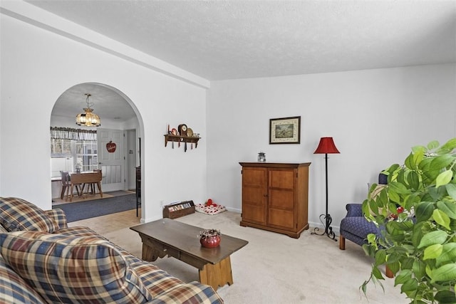 living room with baseboards, light carpet, an inviting chandelier, arched walkways, and a textured ceiling