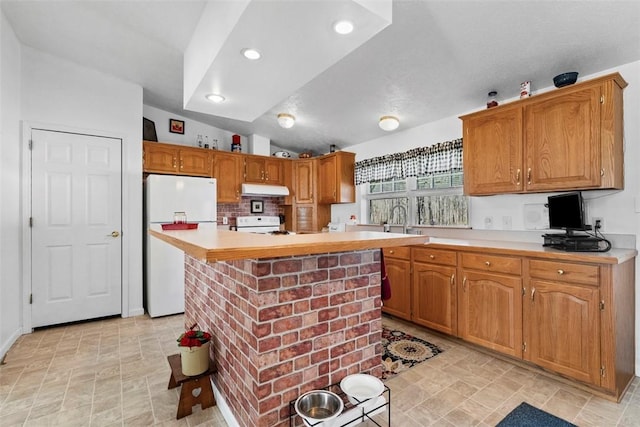 kitchen featuring under cabinet range hood, a sink, white appliances, light countertops, and lofted ceiling