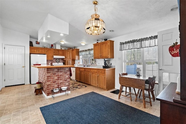 kitchen featuring under cabinet range hood, light countertops, an inviting chandelier, white appliances, and a sink