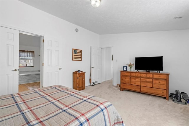 bedroom with light colored carpet, a textured ceiling, ensuite bathroom, and lofted ceiling