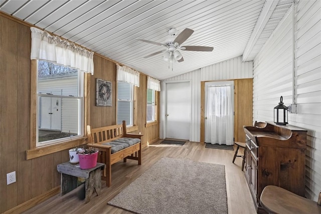 interior space with wood walls, a ceiling fan, light wood-type flooring, and lofted ceiling