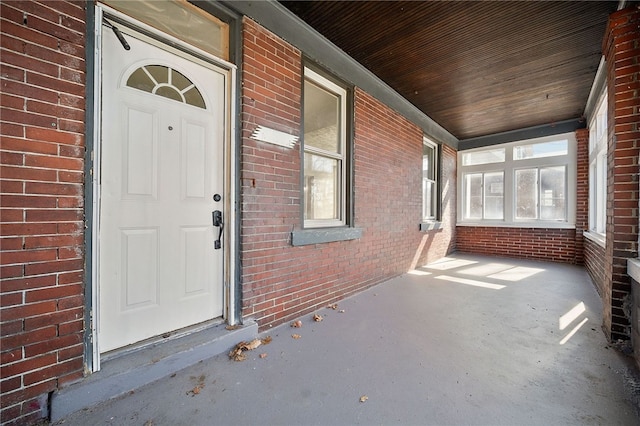 doorway to property with brick siding and covered porch