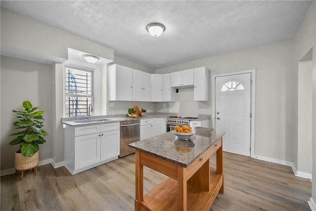 kitchen with light wood finished floors, baseboards, stainless steel appliances, white cabinetry, and a sink