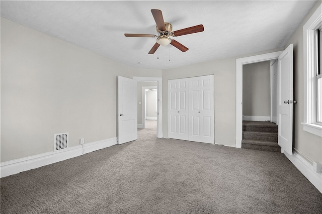 unfurnished bedroom featuring visible vents, a closet, carpet, baseboards, and ceiling fan