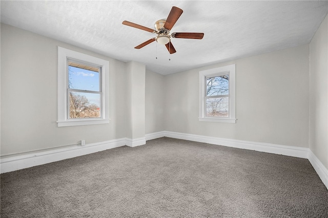 empty room featuring plenty of natural light, a ceiling fan, carpet floors, and a textured ceiling