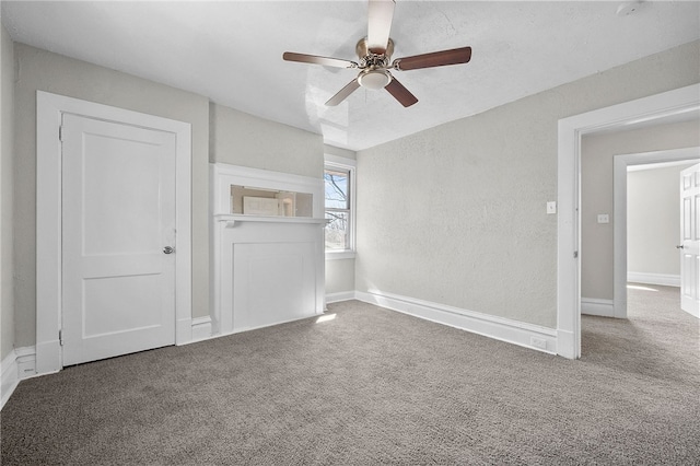 interior space featuring carpet flooring, a ceiling fan, baseboards, and a textured wall