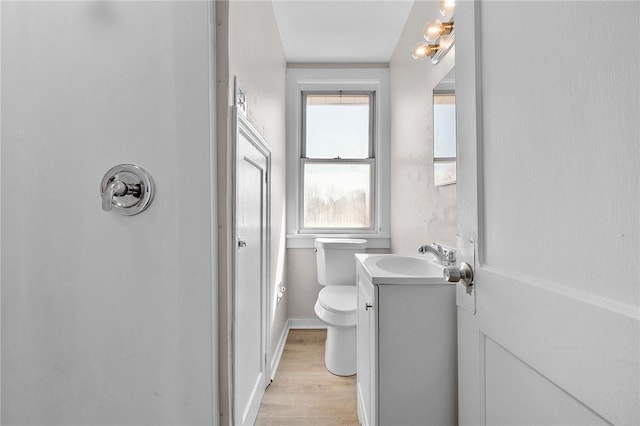 bathroom with toilet, vanity, baseboards, and wood finished floors