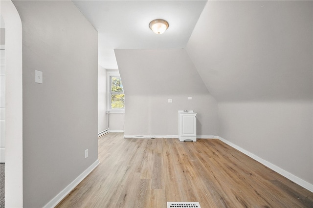 bonus room featuring arched walkways, light wood-style floors, baseboards, and vaulted ceiling