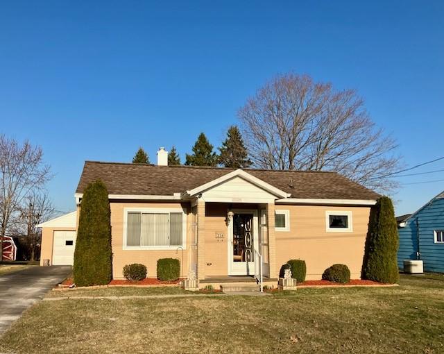 bungalow-style house featuring a chimney, central AC unit, concrete driveway, and a front lawn