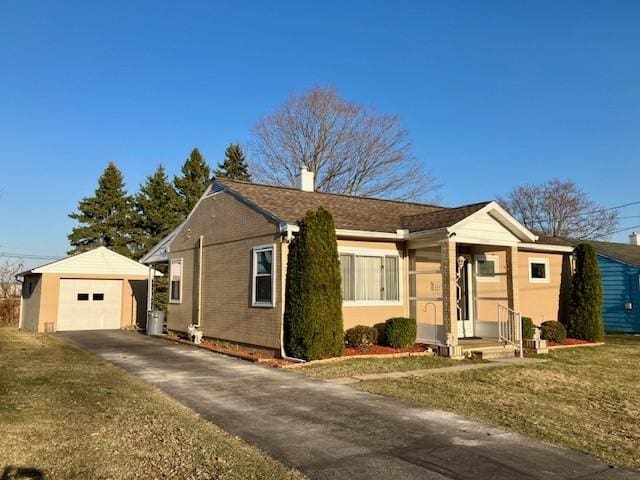 view of front of home featuring an outbuilding, driveway, a chimney, a front lawn, and a garage