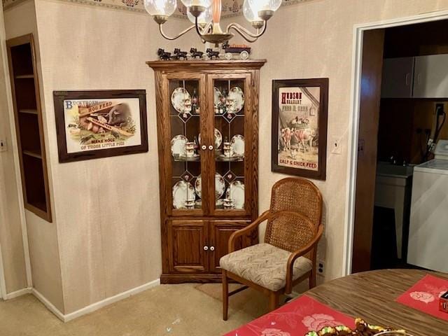 living area with a chandelier, light colored carpet, washer / clothes dryer, and baseboards