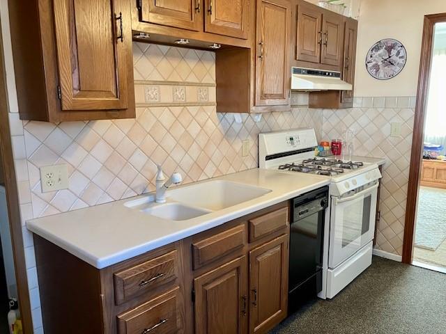 kitchen with under cabinet range hood, dishwasher, light countertops, white gas range oven, and a sink