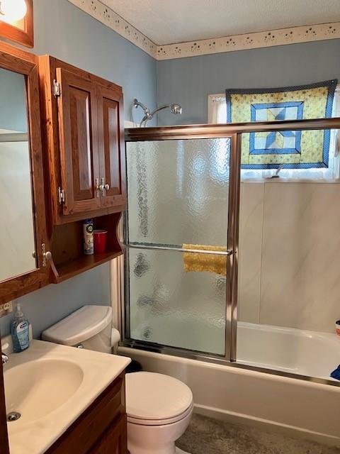 full bathroom with toilet, vanity, and bath / shower combo with glass door