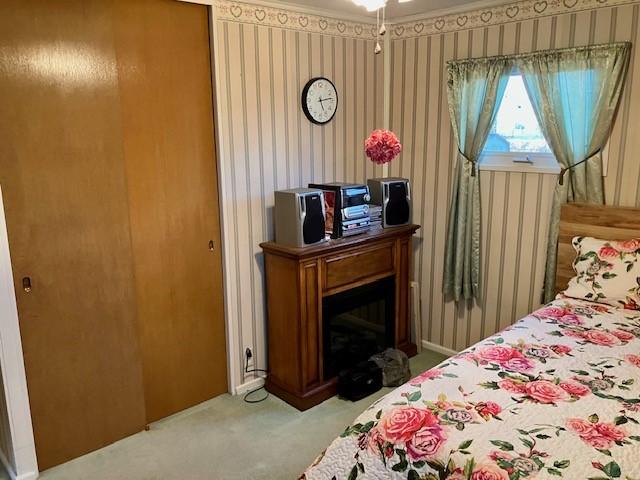 bedroom with carpet, a fireplace, and wallpapered walls