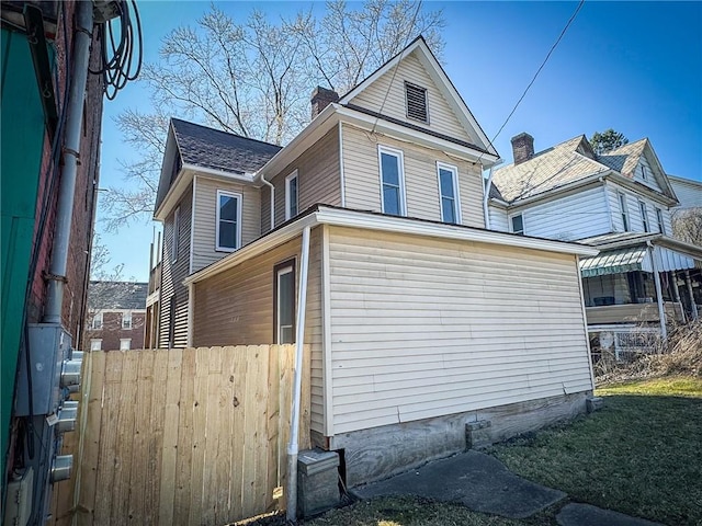 view of side of property with a chimney and fence