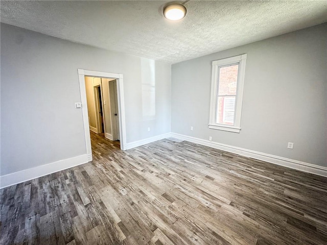 empty room featuring wood finished floors, baseboards, and a textured ceiling