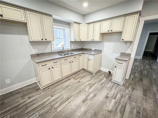 kitchen with a sink, light wood-style floors, baseboards, and cream cabinets