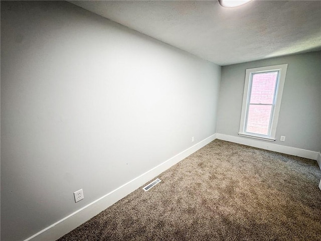 empty room featuring visible vents, baseboards, carpet floors, and a textured ceiling