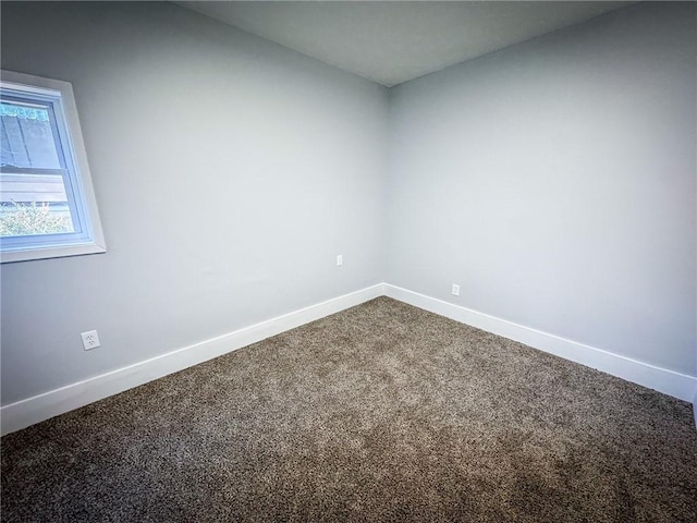 empty room featuring baseboards and dark carpet