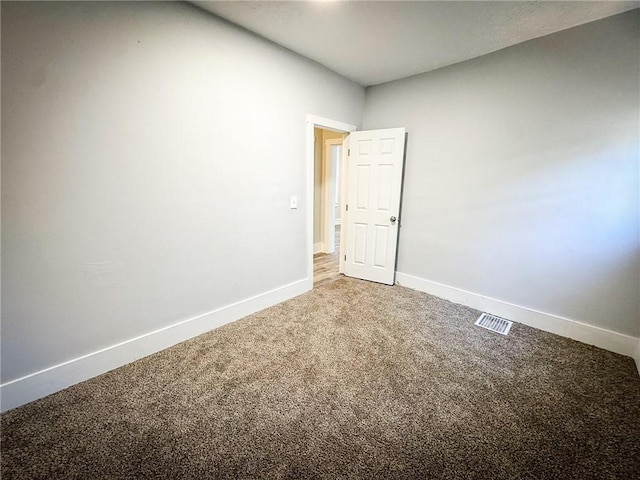 carpeted empty room featuring baseboards and visible vents