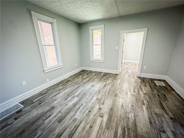 spare room with dark wood finished floors, plenty of natural light, baseboards, and a textured ceiling