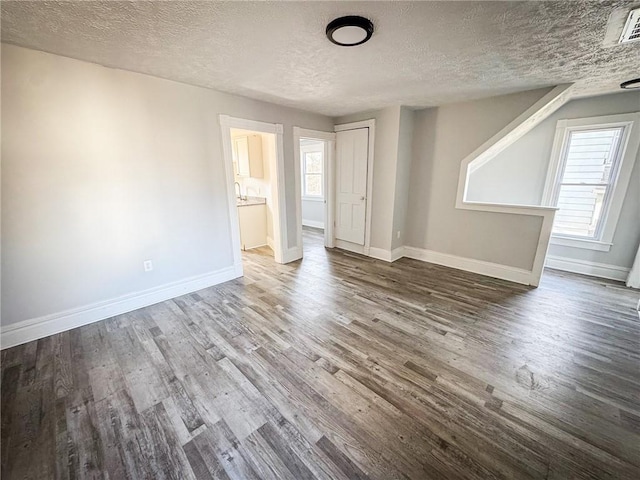 spare room with a textured ceiling, baseboards, and wood finished floors