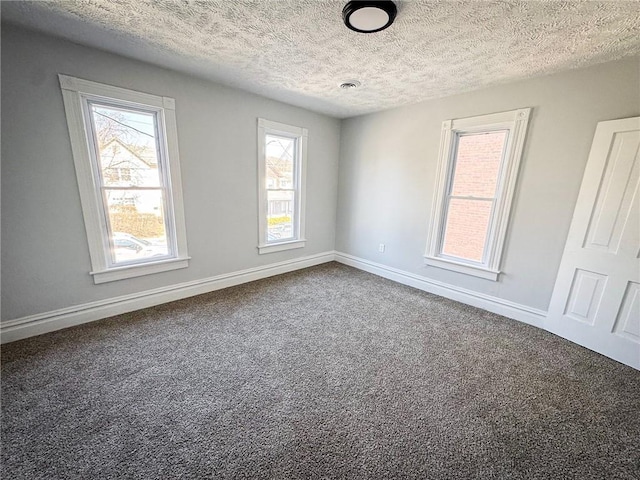 spare room featuring a textured ceiling, baseboards, and carpet