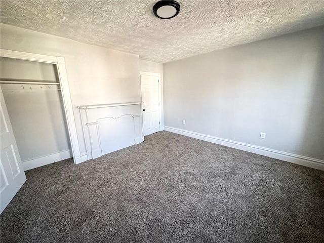 unfurnished bedroom featuring dark colored carpet, a closet, baseboards, and a textured ceiling