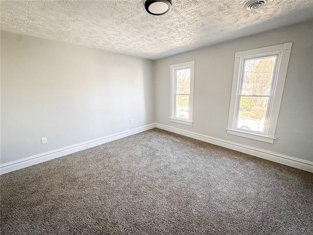 empty room featuring baseboards, carpet floors, a textured ceiling, and visible vents