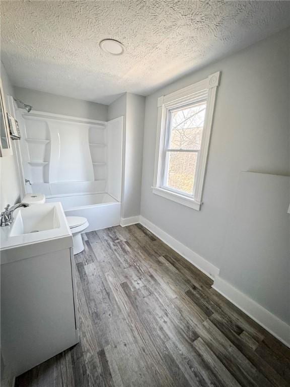 bathroom featuring toilet, shower / tub combination, wood finished floors, baseboards, and vanity