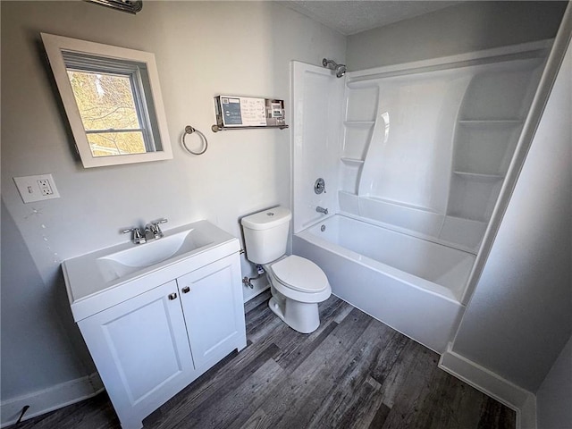 bathroom with baseboards, toilet, shower / bath combination, wood finished floors, and vanity