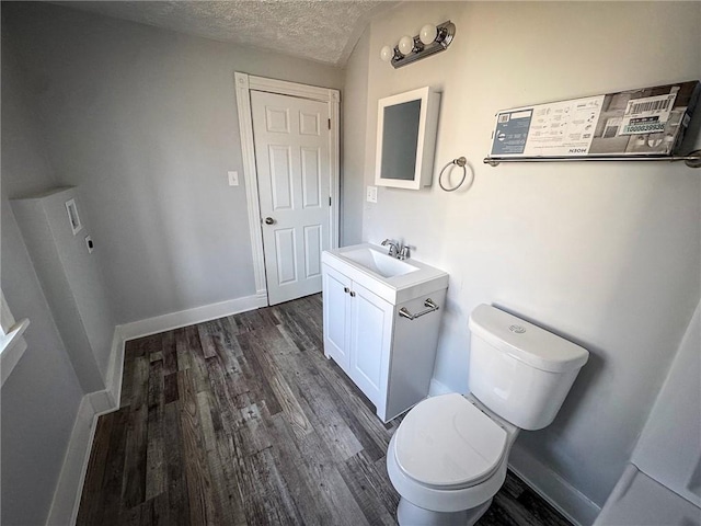 half bathroom with baseboards, a textured ceiling, wood finished floors, and toilet